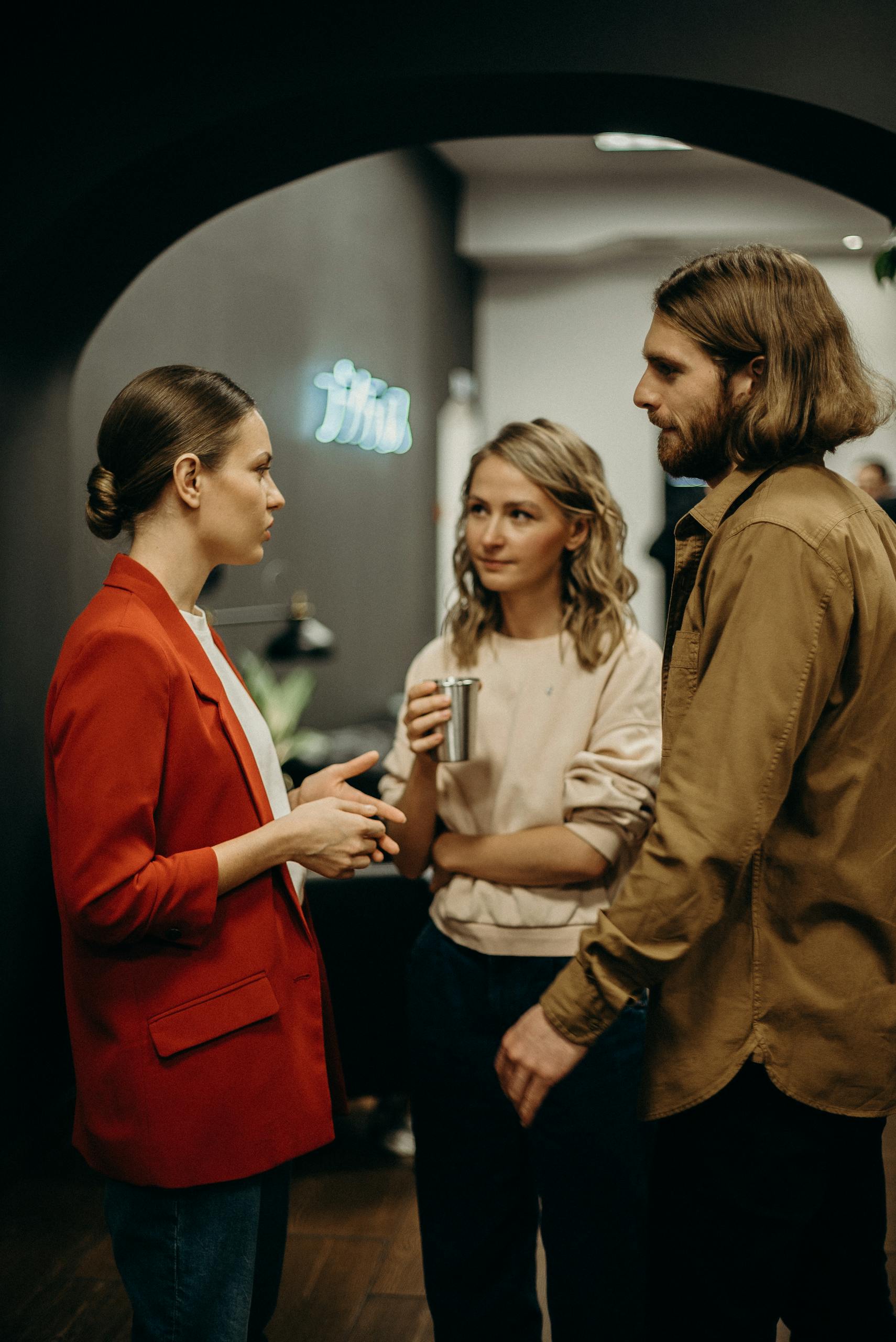 Three colleagues having a discussion in a modern office setting.